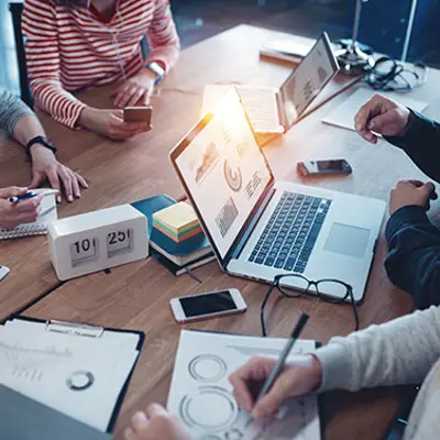 a group of people sitting at a table with office materials on it