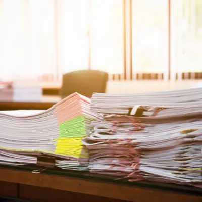 a pile of papers on a desk with sticky notes flagging various sections, bound with clips
