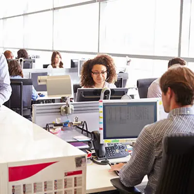 a busy office with various people sitting at their desks in front of computers